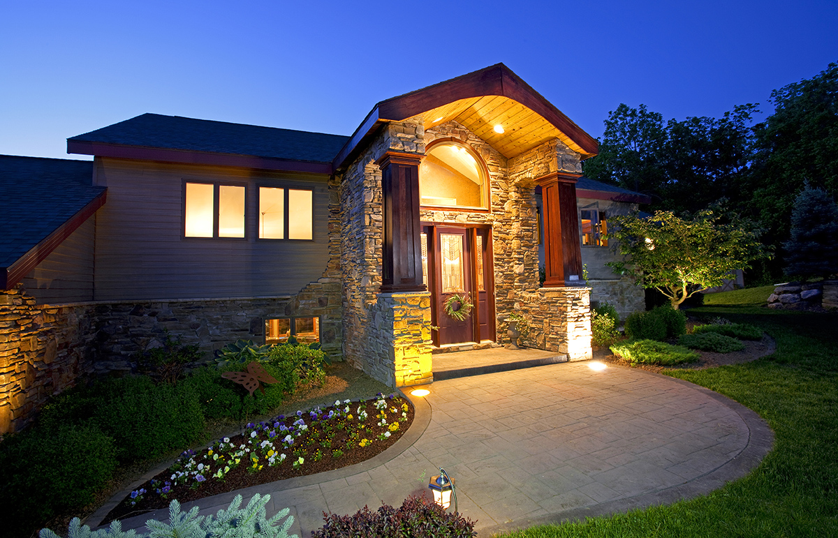 Exterior of a luxury home at dusk with the warm glow of exterior and interior lights.